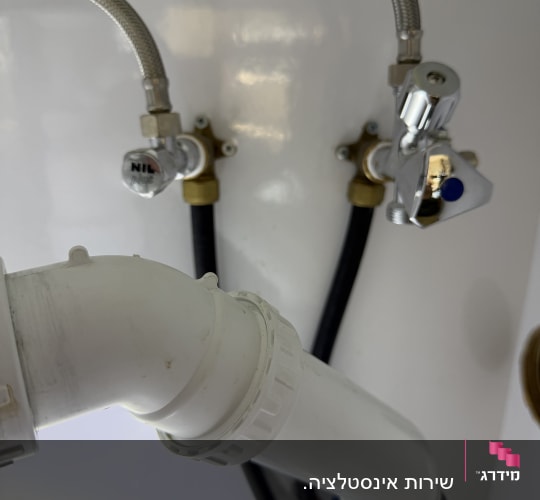צנרת מתחת לכיור עם ברזים וצינורות
